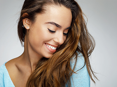 The image shows a close-up of a woman with long hair smiling at the camera.